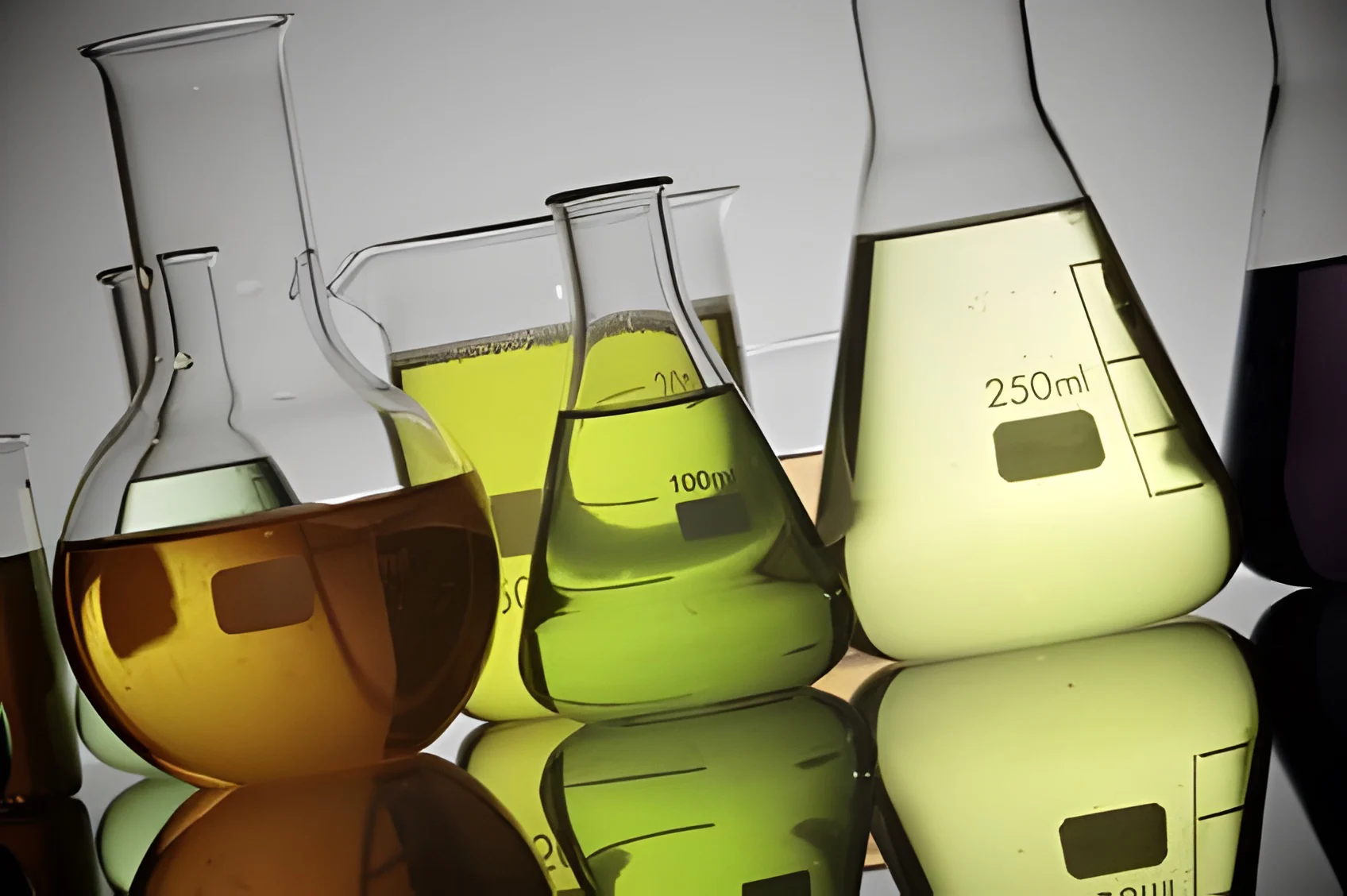 Glass laboratory flasks and beakers filled with yellow, green and amber liquids